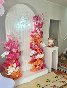 Ripple and floral backdrop arrangment with neon Let's Celebrate