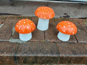 Set of 3 orange concrete mushrooms.